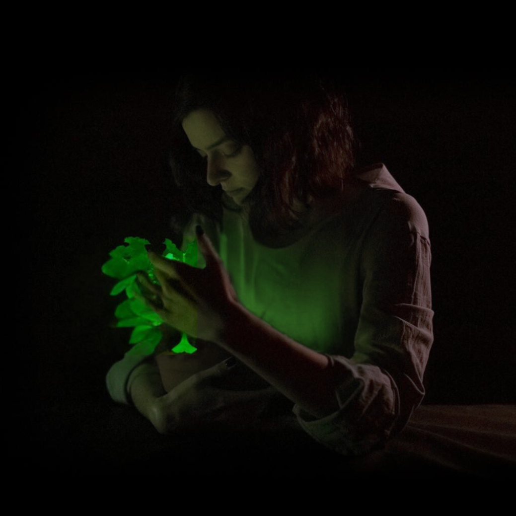 Woman gently holding glowing Firefly Petunia plant in the dark – Light Bio bioluminescent indoor plant